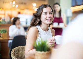 Young woman drinking fresh coffee at table in cafe