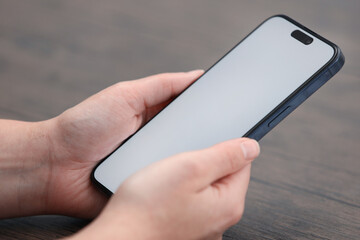 Woman holding smartphone with dialer application at wooden table, closeup