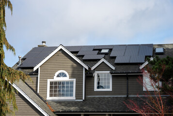 Solar panel array on house roof for green power generation, residential home on sunny winter day
