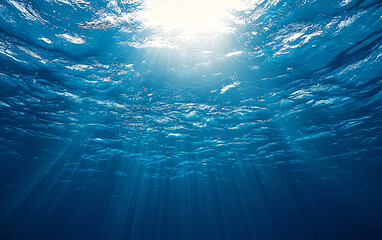 underwater ocean view with sunlight beams piercing through the surface into clear blue water, realistic sea depth background with light rays and marine atmosphere for aquatic designs