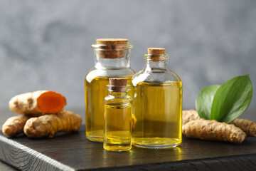 Tumeric oil and roots on black board, closeup