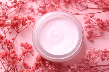 Jar of moisturizing cream among gypsophila flowers on pink background, flat lay
