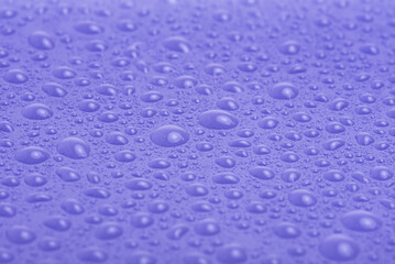 Water drops on purple plastic macro photo.
