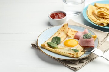 Delicious crepes with egg, ham, basil and sauce on white wooden table, closeup. Space for text