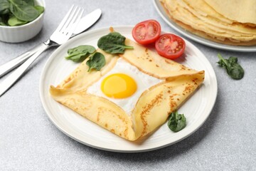 Delicious crepe with egg, tomato and basil on light grey table, closeup