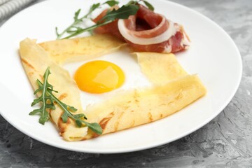 Delicious crepe bretonne with bacon and arugula on grey textured table, closeup