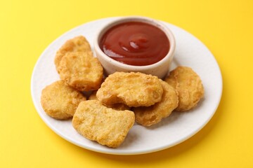 Tasty chicken nuggets with sauce on yellow background, closeup
