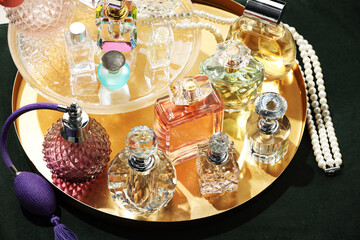 Different luxury perfumes and accessories on green pouf, above view