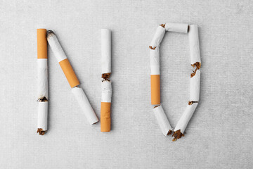 Word NO made with cigarette butts on light gray background, top view