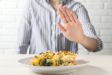 Woman refusing to eat piece of casserole at table, closeup