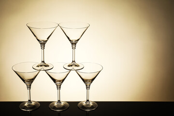 Many empty clean glasses on mirror surface against beige background. Space for text