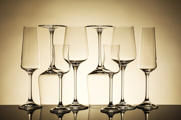 Many empty clean glasses on mirror surface against beige background