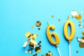 60th birthday. Number shaped candles and confetti on light blue background, flat lay. Space for text