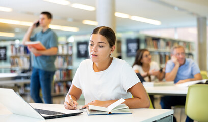Smart female American student preparing for the exam in the school library