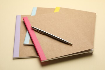 Different copybooks and pen on beige background, closeup