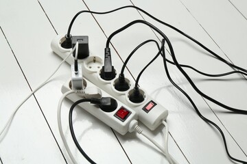Extension power boards overloaded with plugs on wooden floor
