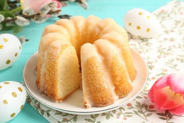 Delicious bundt cake, Easter eggs, willow branches and tulips on light blue table, closeup