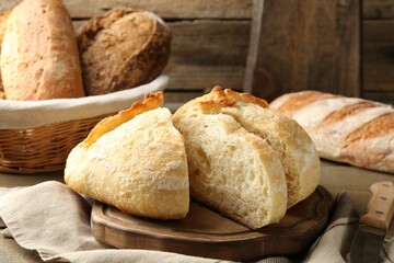 Different loaves of fresh bread, knife and spikes on table, closeup