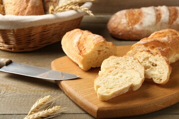 Different types of fresh bread and spikelets on wooden table, closeup