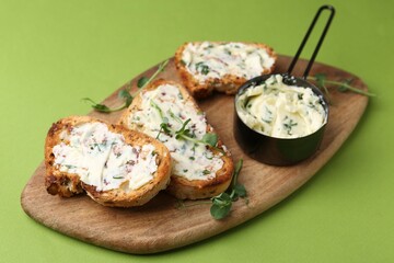 Tasty bread with garlic, herbs and oil on light green background, closeup