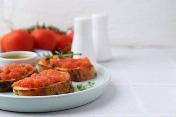 Tasty bread with tomatoes, microgreens and oil on white table, closeup. Space for text