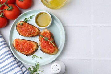 Tasty bread with tomatoes, microgreens and oil on white tiled table, flat lay. Space for text