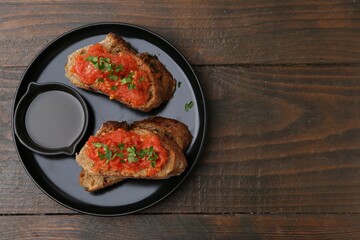 Tasty bread with tomatoes, parsley and oil on wooden table, top view. Space for text