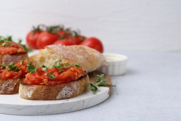 Tasty bread with tomato and parsley on light table, closeup. Space for text