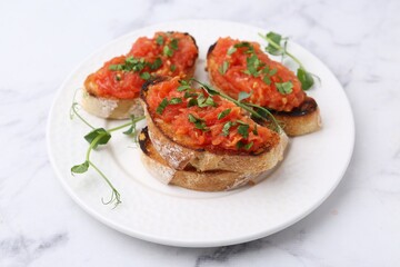 Tasty bread with tomato and parsley on white marble table, closeup
