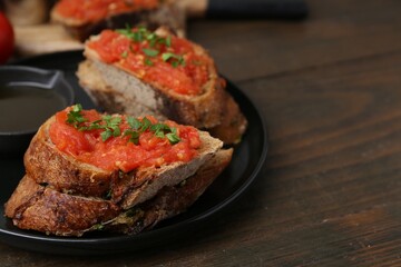 Tasty bread with tomato, parsley and oil on wooden table, closeup. Space for text