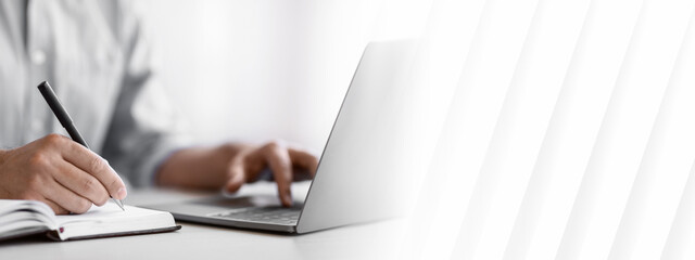 Unrecognizable Man Writing In Notepad And Using Laptop In Office, Taking Notes At Workplace, Using...