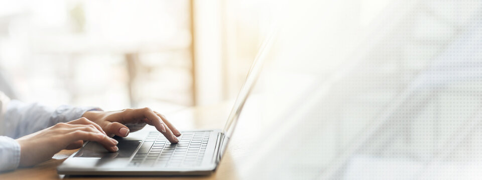 Woman hands typing on laptop over blurred background, side view, freelance concept, cropped, empty space