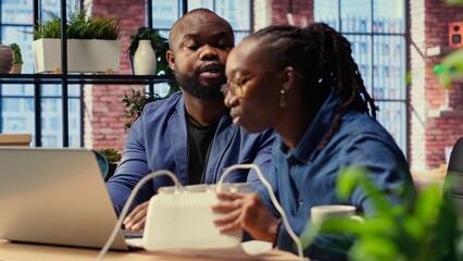 African American angry woman pulling out the LAN cable from the router while her partner reads a...