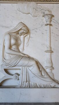 Pisa, Italy. December 20, 2024. Marble relief of a veiled woman in mourning, seated beside an extinguished torch, symbolizing death or loss.