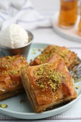 Delicious baklava with crushed nuts and ice cream on white wooden table, closeup