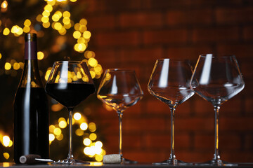 Glass with red wine and empty ones on table against blurred lights. Bokeh effect