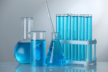 Laboratory glassware with blue liquid on mirror surface against grey background