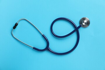 Stethoscope on light blue background, top view