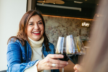 Smiling mature woman enjoying a glass of wine with friends in a cozy restaurant
