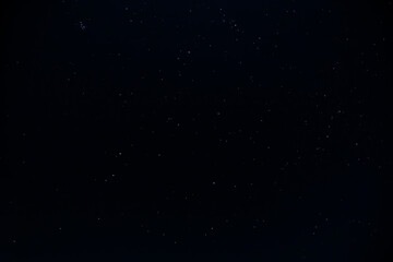 Beautiful bright glowing stars and constellations are scattered across the dark clear sky on a dark...