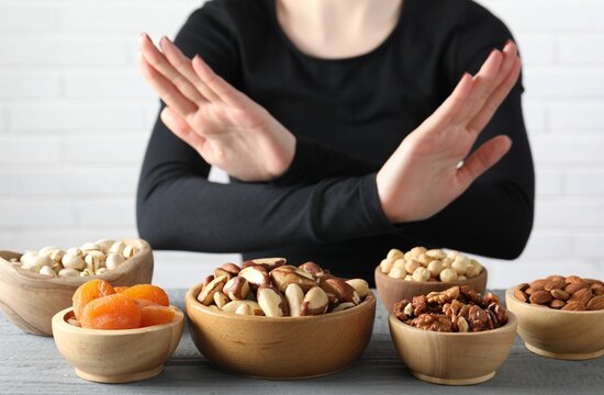 Woman refusing to eat products at grey wooden table, selective focus. Food allergy concept