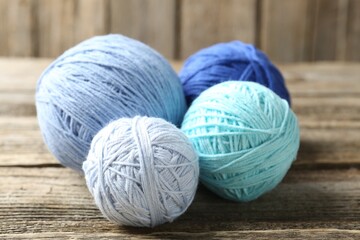 Balls of colorful yarn on wooden table, closeup