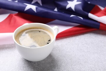Cup of coffee and American flag on light table. Space for text