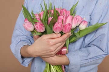 Fototapeta premium Woman with bouquet of beautiful tulips on dark beige background, closeup