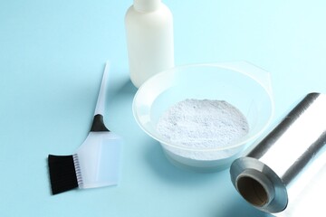 Bleaching powder and hairdresser's tools on light blue background, closeup