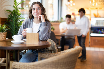 Girl relaxes in cafe, drinks coffee and spends time waiting for meeting. High quality photo