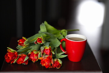 Bouquet of red tulips close-up next to a red cup on the table