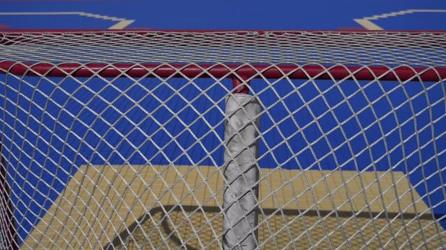 Tilting shot behind a hockey net outside on a dec hockey rink during the spring summer time