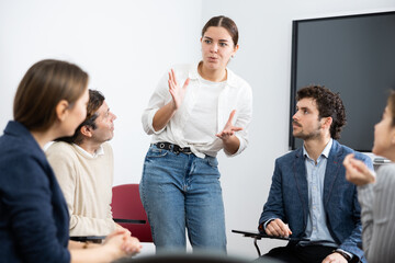 Fototapeta premium Young female teacher giving lecture to group of student