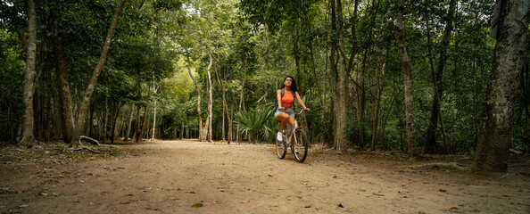 Toma panorámica de una mujer latina hermosa montando en bicicleta en un sendero de la...